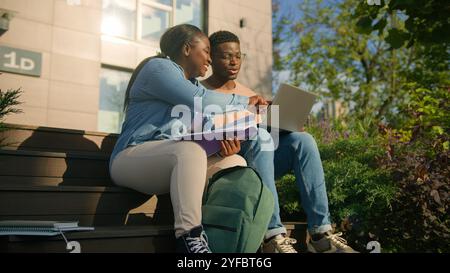 Zwei afrikanische Schüler High School Schüler Mädchen Guy auf dem College Campus draußen im Stadtpark draußen auf der Bank diskutieren Themen zusammen Aufgabe vorbereiten Stockfoto