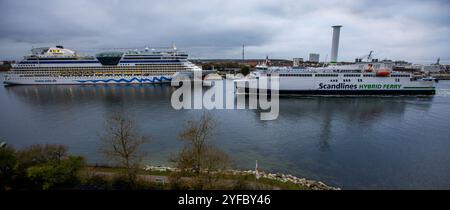 Rostock, Deutschland. November 2024. Die Fähre „Berlin“ (r) passiert das Kreuzfahrtschiff „Aida diva“ durch den vertieften Meereskanal. Seit Oktober 2022 vertiefen Spezialbagger den rund 16 Kilometer langen Meereskanal. Dies kann nun von Schiffen mit einer Tieftiefe von bis zu 15 Metern genutzt werden. Quelle: Jens Büttner/dpa/Alamy Live News Stockfoto