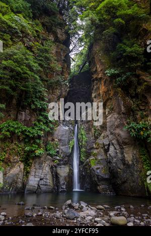 Der Cascata do Salto do Cabrito, versteckt in der üppigen Vegetation von Ribeira Grande, ist ein atemberaubender Wasserfall, der sich durch moosbedeckte Felsen stürzt. Stockfoto