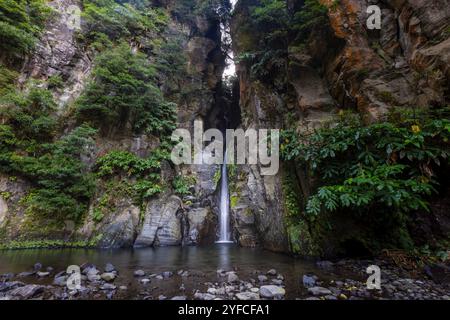 Der Cascata do Salto do Cabrito, versteckt in der üppigen Vegetation von Ribeira Grande, ist ein atemberaubender Wasserfall, der sich durch moosbedeckte Felsen stürzt. Stockfoto