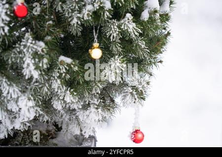 Weihnachtsbaum mit dekorativen Kugeln bedeckt mit Schnee. Stockfoto