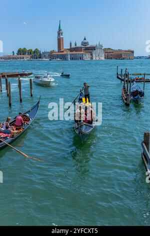 Venedig, Italien - 26. Juli 2024: Gondeln gegen die Insel San Giorgio in Venedig, Italien. Die Gondel ist der attraktivste Touristenverkehr in Venedig. T Stockfoto