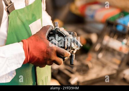 Ein Techniker, der eine mechanische Komponente in einer Werkstatteinstellung hält. Stockfoto