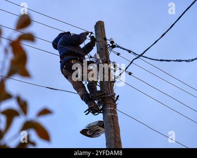 Ein Elektriker, der an einem Elektromast arbeitet. Stockfoto