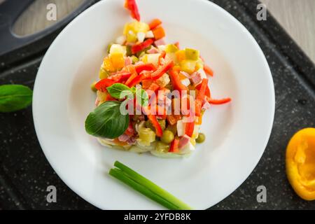 Gemüsesalat aus gekochtem Gemüse, mit Erbsen, Wurst, süßem Pfeffer. Auf einem Holztisch. Stockfoto