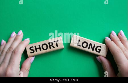 Symbol kurz vs lang. Konzeptwort kurz vs lang auf Holzblöcken. Geschäftsmann Hand. Schöner grüner Hintergrund. Business und kurz- vs Langkonzept. C Stockfoto