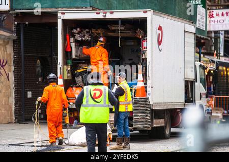 Bauarbeiter in gut sichtbarem Getriebe entladen Ausrüstung von einem Arbeitswagen auf einer Baustelle in New York City, um sich auf die Straße oder Infrastruktur vorzubereiten. Stockfoto
