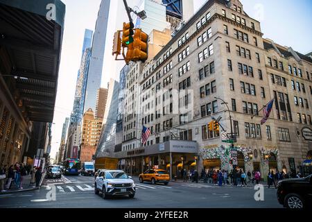 Eine geschäftige Straßenszene an der Kreuzung der Fifth Avenue in New York City mit Fußgängern, Fahrzeugen, gelben Taxis und Wolkenkratzern. Stockfoto