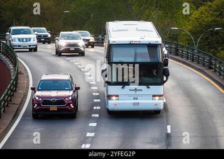 Weißer Van-Hool-Reisebus, der neben anderen Fahrzeugen auf einer kurvenreichen Autobahn fährt. Stockfoto