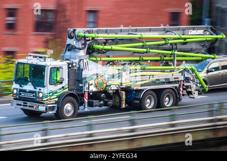 Mack Betonpumpwagen mit verlängerten grünen Rohren, der auf einer Stadtstraße fährt. Stockfoto