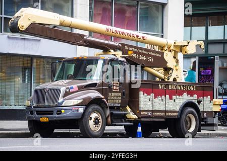 NYC Brownstone Bauwagen mit verlängertem Ausleger, der auf einer Stadtstraße geparkt ist und für die Gebäudewartung genutzt wird. Stockfoto