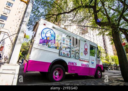 New York Ice Cream Truck in Rosa und weiß, geparkt unter Bäumen auf einer Stadtstraße. Stockfoto