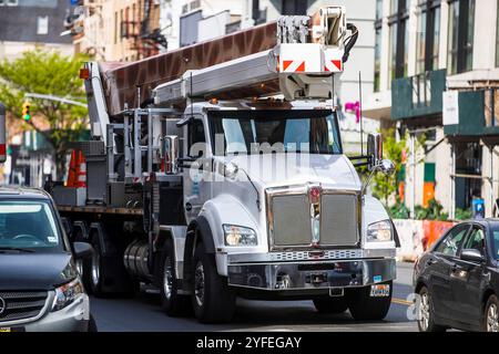 Nutzfahrzeug mit großem Ausleger, der durch eine geschäftige Stadtstraße fährt. Stockfoto