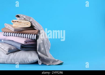 Ein Stapel sauberer Bettlaken und Kissen auf blauem Hintergrund. Platz für Text Stockfoto