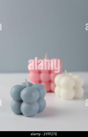 Schöne Bubble Kerzen auf weißem Tisch vor grauem Hintergrund Stockfoto