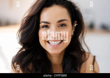 Eine junge Frau mit langen, dunklen Haaren lächelt breit und zeigt ihre perfekten weißen Zähne Stockfoto