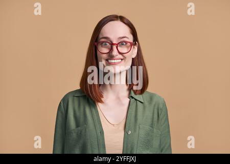 Rothaarige Frau, die eine Brille trägt, ist in einem Moment reiner Freude gefangen, ihre Augen sind weit vor Aufregung und ein breites Lächeln, das ihr Gesicht beleuchtet Stockfoto