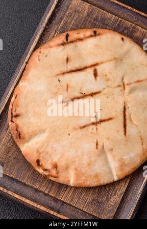 Rundes Fladenbrot oder Pita mit Käse, Kräutern, Salz und Gewürzen, auf dem Grill gebacken Stockfoto