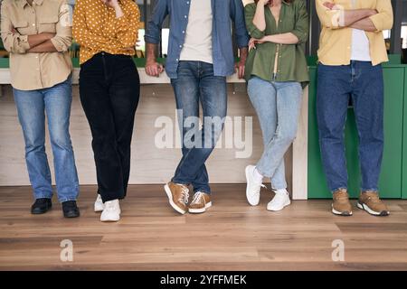 Eine Gruppe junger Berufstätiger macht eine Pause von der Arbeit, steht in einer Reihe und plaudert beiläufig Stockfoto