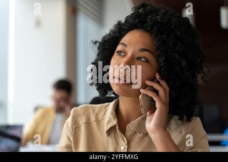Die junge Geschäftsfrau hält ein Telefon an ihr Ohr und hört aufmerksam ihrem Gesprächspartner zu Stockfoto