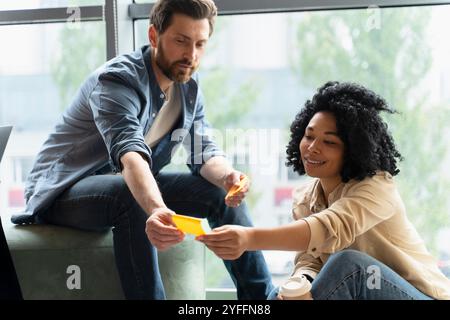 Zwei Geschäftsleute führen ein produktives Meeting und tauschen Ideen und Strategien aus, die auf Klebenotizen geschrieben sind, während sie an einem Projekt arbeiten Stockfoto
