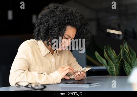 Die junge professionelle Frau hat die Stirn, während sie in einem Büro eine SMS auf ihrem Smartphone liest Stockfoto