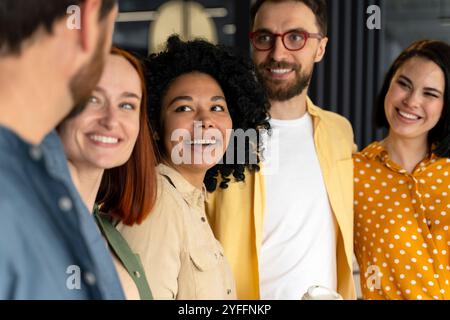 Verschiedene Gruppen von Kollegen stehen nebeneinander, lächeln und genießen die Gesellschaft der anderen bei der Arbeit Stockfoto