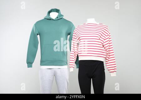 Weibliche und männliche Schaufensterpuppen mit stilvollen Outfits auf hellem Hintergrund Stockfoto