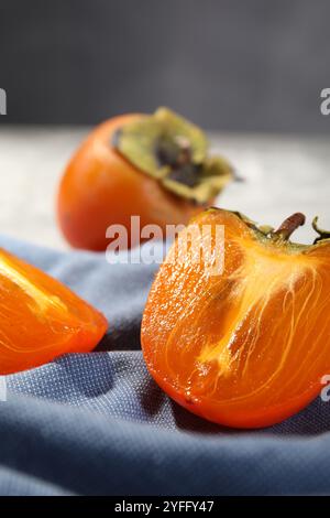 Stücke reifer Persimmonen auf blauem Handtuch, Nahaufnahme Stockfoto