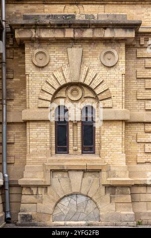 Fenster und Dekorationsdetails einer gelben Ziegelwand, alte Gebäudefassade. Vorderansicht, Hintergrundfotostruktur Stockfoto