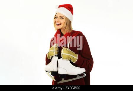 Eislauffrau. Glückliche junge Frau in Winterkleidung mit Schlittschuhen. Wintersport, Wochenenden und Feiertage. Lächelndes Mädchen mit Weihnachtsmütze, warmer Pullover, Stockfoto