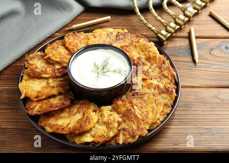 Leckere Kartoffelpfannkuchen mit Sauerrahm auf Holztisch Stockfoto