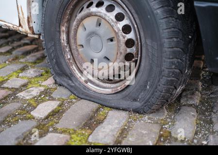 Ein Auto mit Einem flachen Reifen auf Einer Kopfsteinpflasterstraße Stockfoto