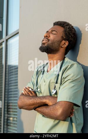 Afroamerikaner Arzt steht vor dem Krankenhaus in Uniform und ruht nach einem harten Tag Stockfoto
