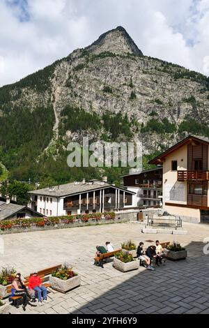 Erhöhter Blick auf die Piazza Abbé Henry, den Hauptplatz der beliebten Bergstadt, mit dem Gipfel des Monte Chetif im Sommer, Courmayeur, Aosta, Italien Stockfoto