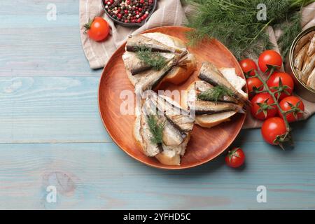 Köstliche Sandwiches mit Sprotten und Dill, serviert auf hellblauem Holztisch, Blick von oben Stockfoto