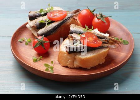 Köstliche Sandwiches mit Sprotten, Mikrogrün und Tomaten auf hellblauem Holztisch, Nahaufnahme Stockfoto