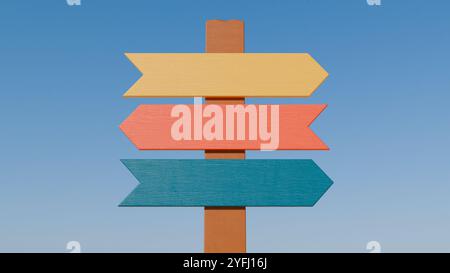 Ein rustikales Holzschild mit drei bunten Pfeilen, die in verschiedene Richtungen gegen einen blauen Himmel zeigen. Stockfoto