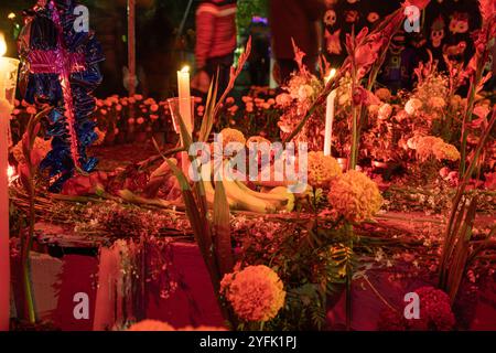 Dia de Muertos Altar mit traditionellem Brot, Ringelblumen und Kerzen, symbolisiert Opfer, um verstorbene Seelen zu ehren. Beleuchtete Ofrenda Stockfoto