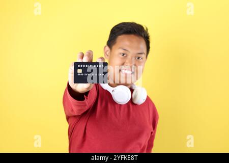 Übergewichtiger asiatischer Junge mit schwarzer Karte, isoliert auf gelbem Hintergrund Stockfoto