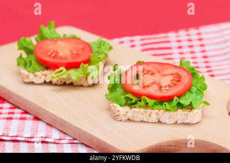 Reiskuchen-Sandwiches mit Tomaten und Salat auf Holzbrett. Einfaches Frühstück. Diät-Essen. Schnelle und gesunde Sandwiches. Knäckebrot mit leckerer Füllung. Gesunder Ernährungs-Snack Stockfoto