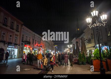 NOVI SAD, SERBIEN - 18. DEZEMBER 2022: Selektive Unschärfe auf Menschen, die an der Straße Zmaj Jovina Ulica vorbeilaufen, die Fußgängerzone Novi Sad nachts in der e Stockfoto