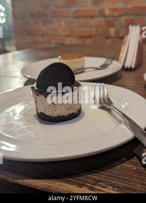 Oreo-Käsekuchen mit einer Gabel an der Seite und einem halben Oreo-Topping in der Bäckerei Stockfoto