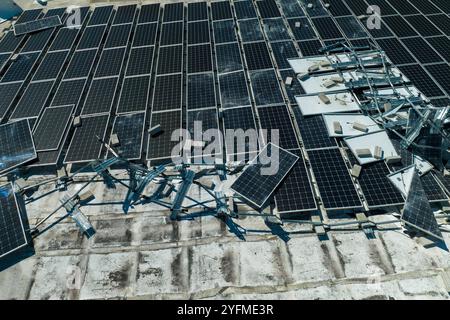 Luftaufnahme von durch Hurrikan-Wind beschädigten Photovoltaik-Solarpaneelen auf dem Dach von Industriegebäuden zur Erzeugung von ökologischem Strom. Kontra Stockfoto