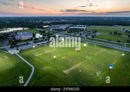 Öffentliches Sportstadion mit jungen Leuten, die bei Sonnenuntergang ein Fußballspiel spielen. Aktives Lebenskonzept. Stockfoto