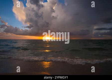 Ozeanlandschaft mit Gewitterwolken über rauen abendlichen Meerwasserwellen, die am Sandstrand zerquetschen. Wunderschöne Meereslandschaft bei Sonnenuntergang. Stockfoto