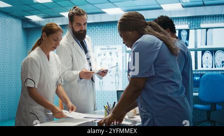 Das Healthcare-Team diskutiert menschliche Anatomie und diagnostische Strategien in einer medizinischen Praxis. Durch die kollektive Arbeit werden genaue Behandlungspläne und professionelle Lösungen sowie Fachkenntnisse in der Radiologie sichergestellt. Kamera B.. Stockfoto
