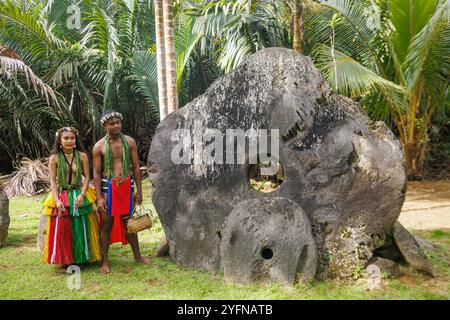 Einheimisches Yapese-Paar in traditioneller Kleidung, abgebildet mit Steingeld in ihrem Dorf auf der Insel Yap, Mikronesien. Stockfoto