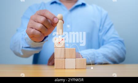 Hand Mann Platzierung hölzerne Spitze des Staates oder der Gewinner, Konzept des Erfolgs, Gewinnen und Leistung im Geschäft. Ein Mann, der ein hölzernes Puppenmodell hält Stockfoto