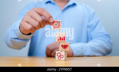 Holzblockstapelung mit einer Hand, die eine Geschäftsstrategie und einen Aktionsplan darstellt. Ausrichtung auf das Konzept des Verfahrens und der systematischen Arbeit Stockfoto
